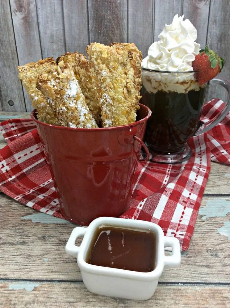 Air Fryer French Toast Sticks ready to serve in a red bucket with ice coffee on a table with a red towel